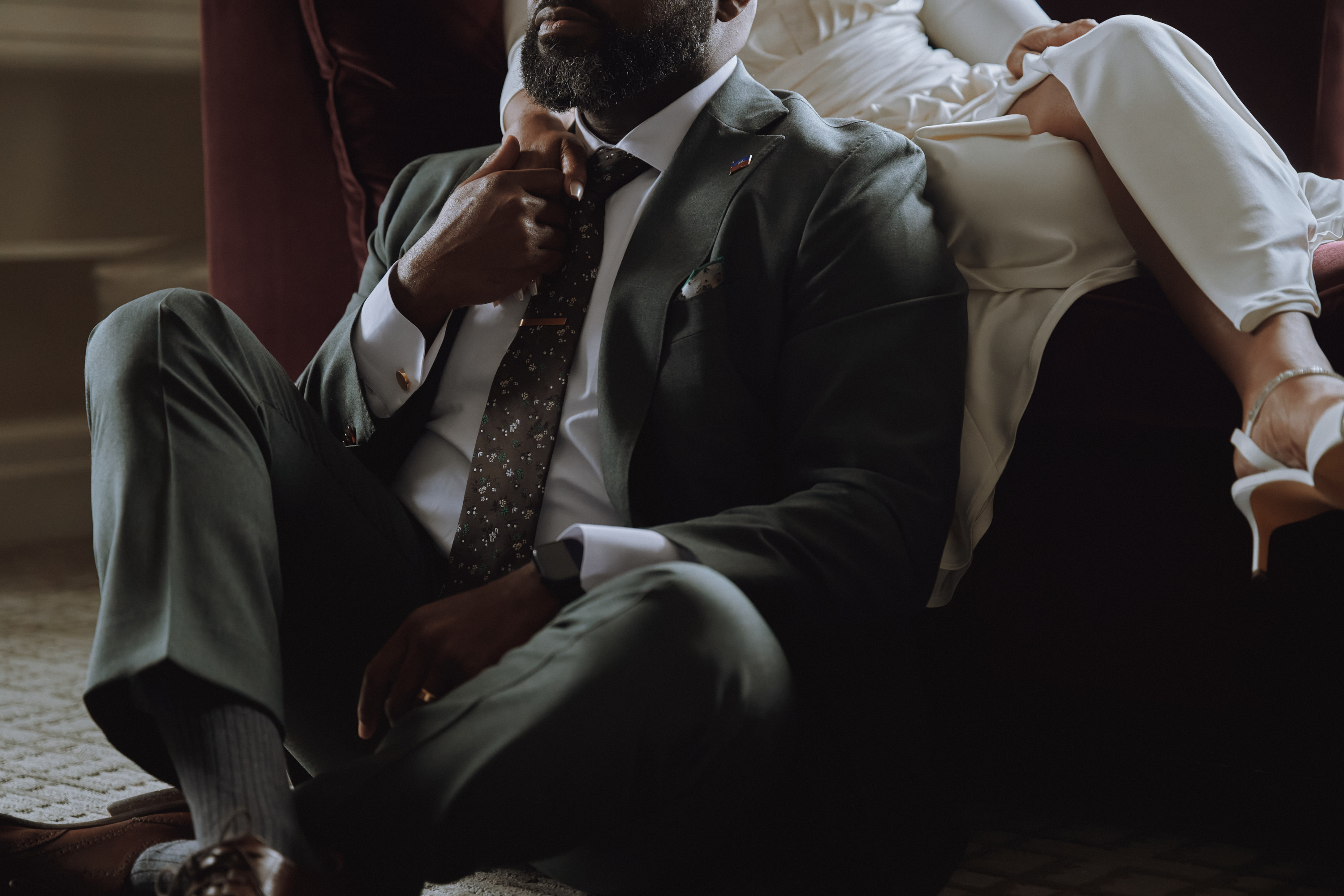 Candid black and white wedding photo of a groom sharing a moment with family